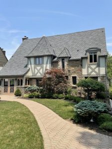 View of a beautiful home with shingle roofing and stone siding 