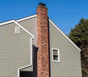 Sideview of a home with a tall brick chimney along its exterior 