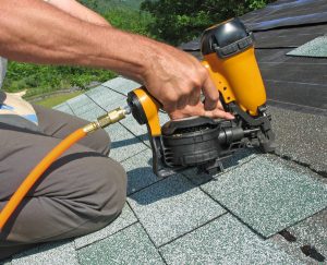 Picture of a roofing technician repairing an asphalt shingle roof.