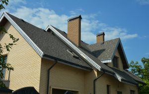 Picture of a brick house with an asphalt shingle roof and two brick chimneys.